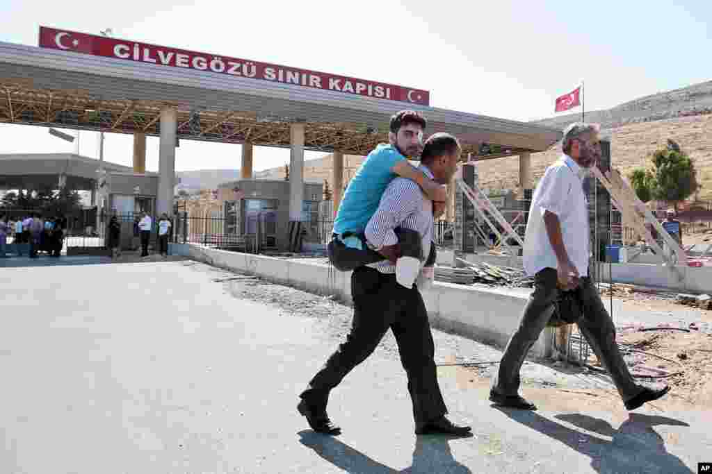 Anh Mustafa Abu Bekir được người thân cõng qua cửa khẩu biên giới Cilvegozu ở Thổ Nhĩ Kỳ, ngày 9 tháng 9, 2013.