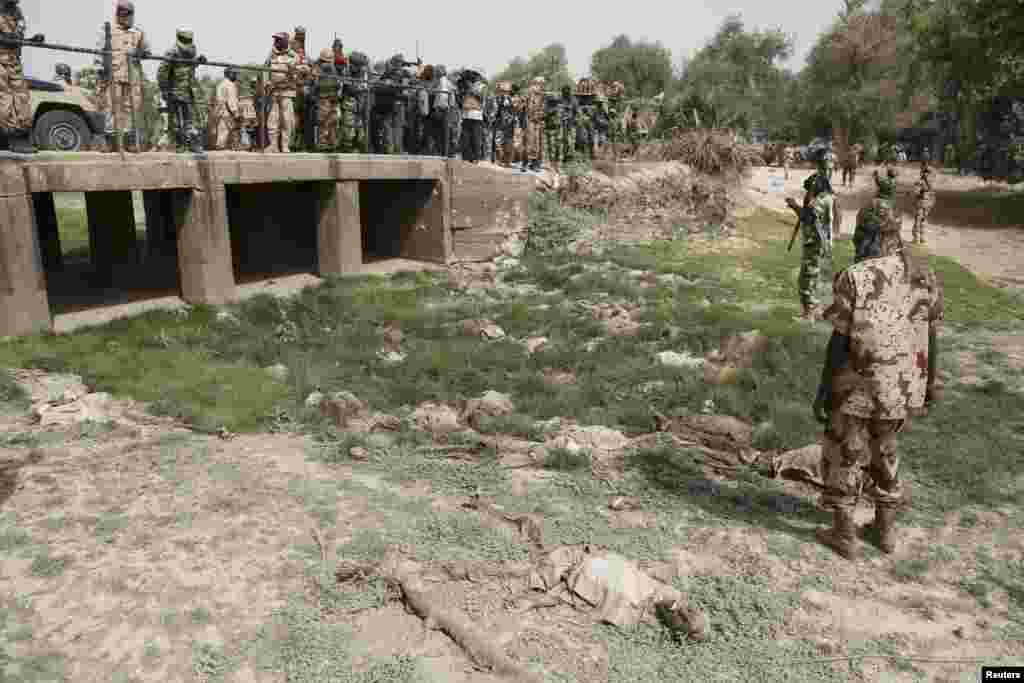 Des soldats tchadiens et nigériens observent des cadavres en décomposition dans une fosse commune dans la ville de Damasak récemment reprise de mains de Boko Haram, le Nigeria, vendredi 20 mars 2015.