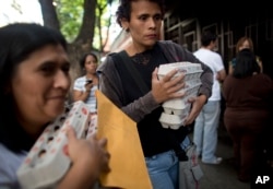 FILE - People carry boxes of eggs after buying them at government regulated prices in Caracas, Venezuela, during an egg shortage, Jan. 27, 2016. Venezuela's opposition-controlled parliament said Wednesday that inflation in the first seven months of 2017 was 248.6 percent.