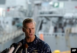 Vice Adm. Joseph Aucoin, commander of the U.S. 7th Fleet, speaks during a press conference, with the damaged USS Fitzgerald in the background at the U.S. Naval base in Yokosuka, southwest of Tokyo, June 18, 2017.