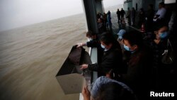 A man scatters the ashes of his parents and grandmother into the ocean during a sea burial ceremony near Shanghai, May 10, 2014.