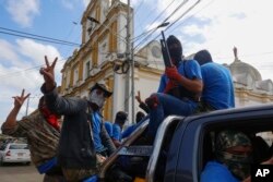 FILE - Armed pro-government militia members flash victory signs as they occupy the Monimbo neighborhood of Masaya, Nicaragua, July 18, 2018.