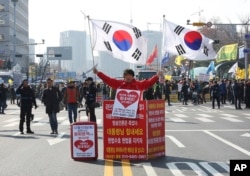 A supporter of South Korean President Park Geun-hye holds the national flags during a rally opposing the parliamentary impeachment of Park in front of the National Assembly in Seoul, South Korea, Dec. 9, 2016. The signs read "Oppose the impeachment."
