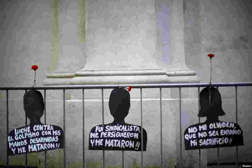 Cut-outs depicting victims of human rights abuse during the rule of former dictator Augusto Pinochet hang on a fence next to the &quot;La Moneda&quot; Presidential Palace during a rally in Santiago. Friday marked the 42nd anniversary of the coup d&#39;etat in Chile that ushered in a 17-year dictatorship under Pinochet.