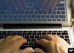 FILE - Hands type on a computer keyboard in Los Angeles, Feb. 27, 2013.