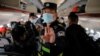 FILE - A police officer orders Reuters journalists off the plane before all other passengers without explanation while the plane is parked on the tarmac at Urumqi airport, Xinjiang Uyghur Autonomous Region, China, May 5, 2021. 