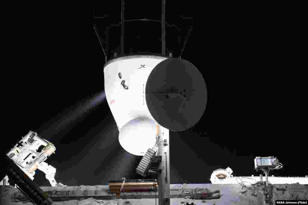 The SpaceX Cargo Dragon resupply ship's Draco engines fire following its detachment from the International Space Station's Harmony module's space-facing port.