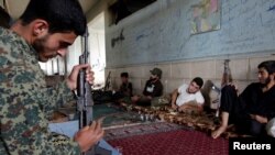 2016年5月17日，什叶派的反抗组织的一名战士在叙利亚南部的一个村庄擦拭武器，准备战斗。