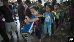 Niñas hondureñas se abrazan mientras esperan en la fila la oportunidad de jugar en el patio de recreo en un campamento establecido por una caravana de miles de migrantes centroamericanos en Juchitán, México, 31 de octubre de 2018.