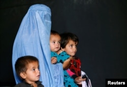 FILE - An Afghan family, returning from Pakistan, watch a short video clip about mines during a mines and explosives awareness program at a United Nations High Commissioner for Refugees (UNHCR) registration centre in Kabul, Sept. 27, 2016.