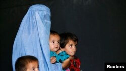 FILE - An Afghan family, returning from Pakistan, watch a short video clip about mines during a mines and explosives awareness program at a United Nations High Commissioner for Refugees (UNHCR) registration centre in Kabul, Sept. 27, 2016. 