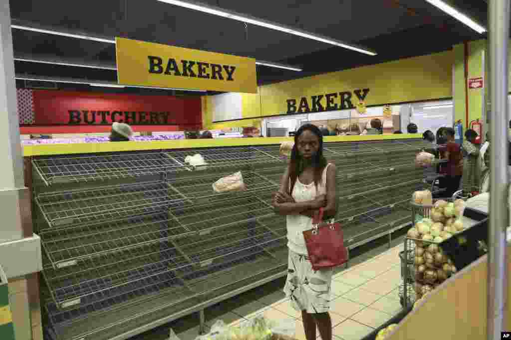 A woman walks past almost empty bread shelves in a shop in Harare, Oct. 9, 2018. As Zimbabwe plunges into its worst economic crisis in a decade, gas lines are snaking for hours, prices are spiking and residents goggle as the new government insists that the country somehow has risen to middle income status.