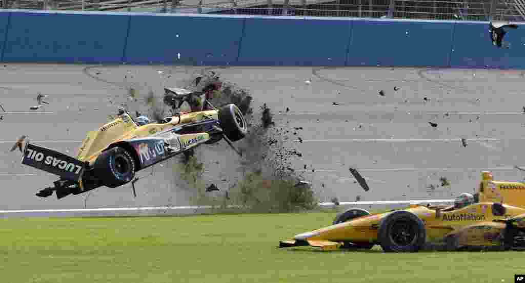 Ryan Briscoe, (esq) rompe pela relva com o seu carro durante a corrida IndyCar no Auto Club Speedway em Fontana, Califórnia, 27 de Junho, 2015.