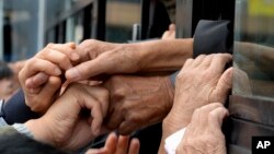 FILE - South Koreans and their North Korean relatives on a bus grip hands to bid farewell after the Separated Family Reunion Meeting at Diamond Mountain resort in North Korea, Oct. 22, 2015. Hundreds of elderly Koreans wept and embraced as they parted — perhaps for good — after briefly reuniting for the first time in more than 60 years. 