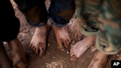 FILE - Displaced Syrian children gather barefoot in a refugee camp near Atma, Idlib province, Syria.