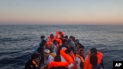 FILE - Refugees and migrants overcrowd a wooden boat during a rescue operation on the Mediterranean sea, about 19 miles north of Az Zawiyah, Libya on July 21, 2016.