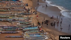 FILE - People are pictured on a beach next to fishing canoes in Dakar, Senegal, June 21, 2013. 