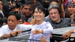 Burma's opposition leader Aung San Suu Kyi (C) waves to the crowd as she leaves National League for Democracy (NLD) headquarters after addressing journalists and supporters in Rangoon on April 2, 2012.