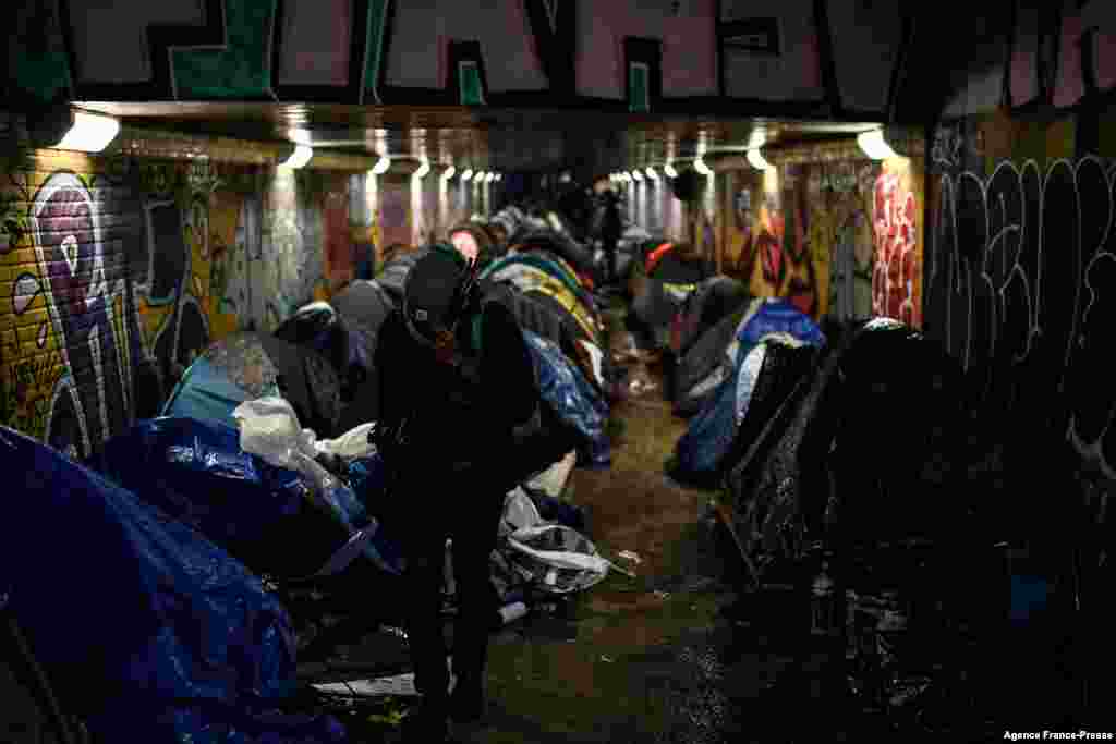 A migrant carries his belongings at a makeshift camp set up under a pedestrian tunnel passing underneath the ring road during an evacuation operation between Paris and the northeastern suburb of Le Pre Saint Gervais.