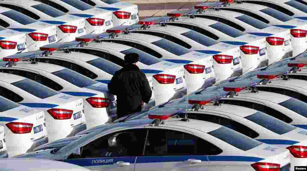 A police officer walks amidst cars during a ceremony for the handover of new vehicles to the personnel of the Ministry of Internal Affairs in Stavropol, Russia.