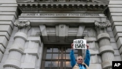 FILE - Karen Shore holds up a sign outside of the 9th U.S. Circuit Court of Appeals in San Francisco, Feb. 7, 2017. 