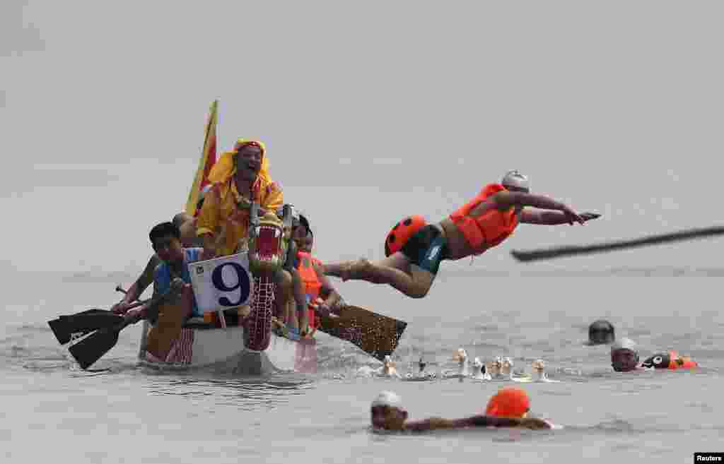 A participant jumps into the river to catch ducks and geese during a competition to celebrate the Dragon Boat Festival on a section of the Yangtze River in Yibin, Sichuan province, China.