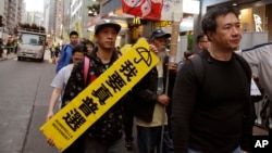 Pro-democracy protesters carry a sign reading "I want genuine universal suffrage" during a demonstration in Hong Kong, March 25, 2017. Hong Kong is poised to choose a new leader Sunday when members of a committee dominated by elites favored by Beijing cast their ballots in the first such vote since 2014's huge pro-democracy protests. 