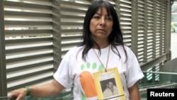 Luz Elena Galeano poses during a interview in Medellin, Colombia, July 15, 2015. Galeano has been searching for her husband (whose photo is hung around her neck) since 2008. 