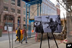 A photo from April 6, 1968, showing pedestrians being waved away from a barred area by a gas-masked National Guard member guarding the area is placed on a easel near the present day corner of 7th and K Streets, in northwest Washington, on March 25, 2018.