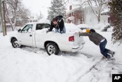 Alex Flores (L) helps his friend Taylor Riggs (R) free up his truck from the snow in Lexington, Kentucky, March 5, 2015.
