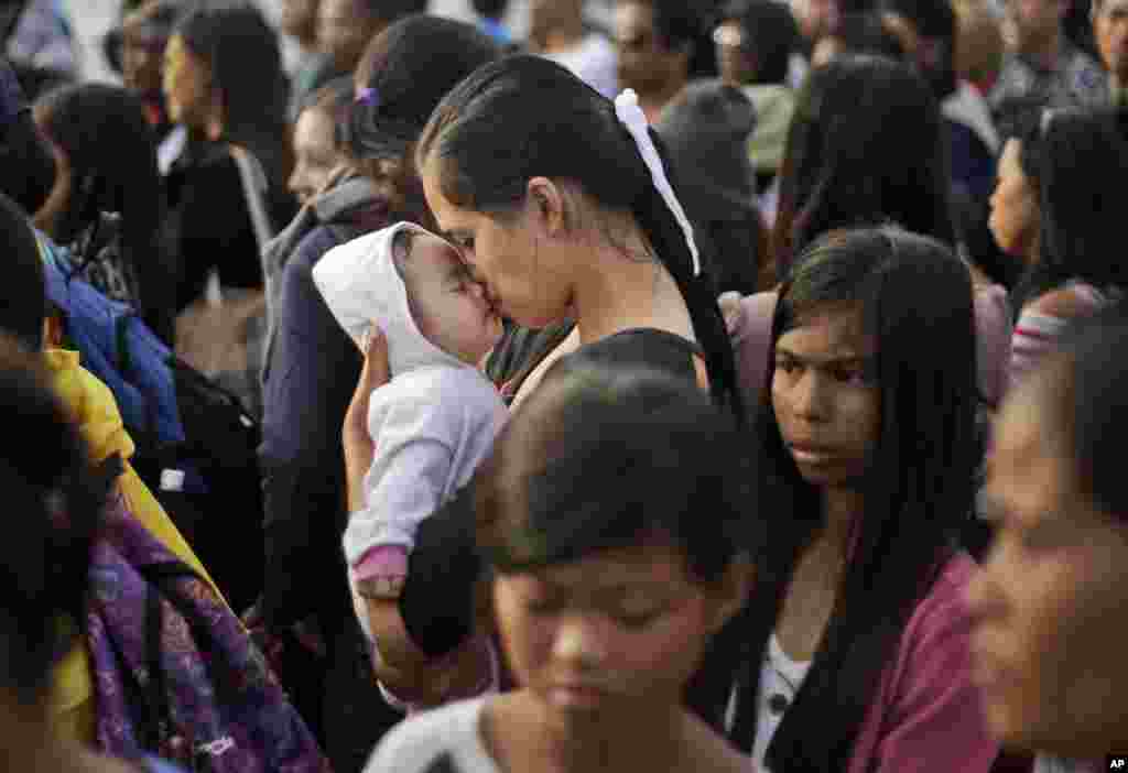 A Typhoon Haiyan survivor kisses her baby as she waits to board her evacuation flight at the airport in Tacloban, Philippines. 