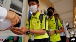 FILE - Students sanitize hands to avoid the contact of coronavirus before their morning class at a high school in Phnom Penh, Cambodia, Tuesday, Jan. 28, 2020.