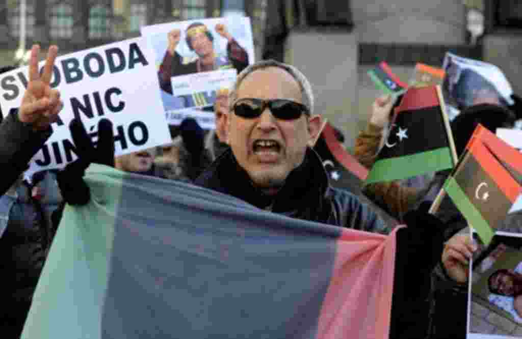Libyans living in Prague, Czech Republic hold banners and Libya's old national flags as they shout slogans during a protest against the Libyan leader Moammar Gadhafi and condemned the bloody crackdown on the protesters, February 25, 2011