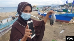 Ibu Mardia Djaelangkara, warga Talise, memperlihatkan ikan katombo yang dibeli dari nelayan untuk dijual kembali menggunakan platform media sosial. Sabtu, 19 Desember 2020. (Foto: VOA/Yoanes Litha)