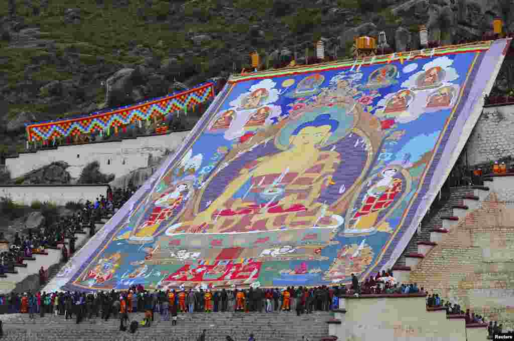 Tibetan Buddhists and tourists view a huge Thangka, a religious silk embroidery displaying a Buddha portrait, during the Shoton Festival at Drepung Monastery in Lhasa, Tibet Autonomous Region, China.