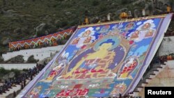 Tibetan Buddhists and tourists view a huge Thangka, a religious silk embroidery or painting displaying a Buddha portrait, during the Shoton Festival at Drepung Monastery in Lhasa, Tibet Autonomous Region, China, Aug. 14, 2015.