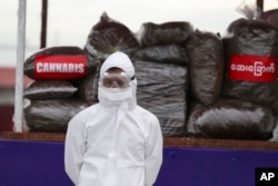 အျပည္ျပည္ဆိုင္ရာ မူးယစ္ေဆးဝါးအလဲြသုံုးမႈနဲ႔ တရားမ၀င္ တိုက္ဖ်က္ေန႔အခမ္းအနားမွာ ေတြ႔ရတဲ့ PPE ၀တ္စံုျပည့္၀တ္ထားတဲ့ ရဲတပ္ဖဲြ႔၀င္တဦး။ (ဇြန္ ၂၆၊ ၂၀၂၀)