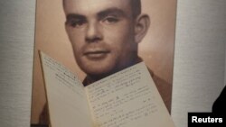 FILE - A notebook of British mathematician and pioneer in computer science Alan Turing is displayed in front of a photo of him during an auction preview in Hong Kong.