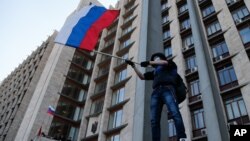 Un manifestante prorruso ondea una mandera rusa en frente de un edificio administrativo en Donetsk, Ucrania, exigiendo anexión a Rusia.