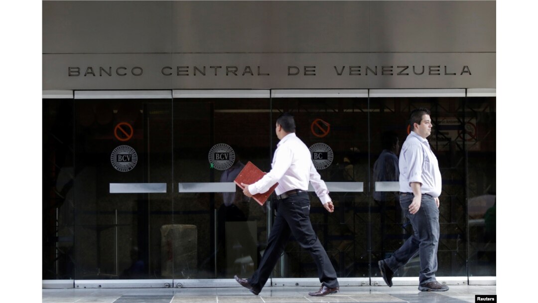 FILE - People walk past an entrance of the Venezuela's Central Bank in Caracas, Venezuela, June 22, 2017.