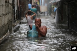 A resident carries a tank of liquified petroleum gas as he negotiates a flooded area while Typhoon Rammasun nears suburban Quezon city, Philippines, July 16, 2014.