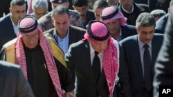 Jordanian King Abdullah II (C), escorted by Safi al-Kaseasbeh (L), father of slain Jordanian pilot, Lt. Muath al-Kaseasbeh, and the pilot's uncle Fahed al-Kaseasbeh, arrive at a memorial tent at their home village of Ai, Jordan, Feb. 5, 2015.