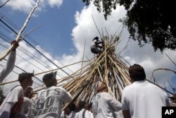 A man stands on a cone of sticks during a Hindu ritual called "Mekotek," a traditional stick fighting ceremony used to celebrate the triumph of good over evil, in Bali, Indonesia, Saturday, Nov. 11, 2017.