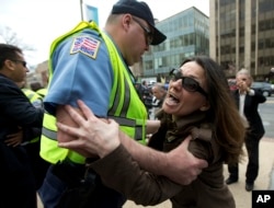 Anti-Erdogan protester Deniz Lohja, an American of Turkish descent, is prevented by a Washington police officer from crossing near the supporters of the Turkish President Recep Tayyip Erdogan, during a rally outside the Brookings Institution in Washington, March 31, 2016, where Erdogan spoke.