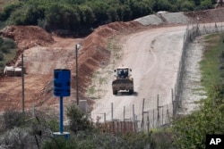 An Israeli bulldozer makes sand barriers on a road to an Israeli settlement, during a media trip organized by Hezbollah to show journalists the defensive measures established by the Israeli forces to prevent against any Hezbollah infiltration into Israel, April 20, 2017.