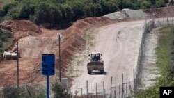 An Israeli bulldozer makes sand barriers on a road to an Israeli settlement, during a media trip organized by Hezbollah to show journalists the defensive measures established by the Israeli forces to prevent against any Hezbollah infiltration into Israel, at the Lebanese-Israeli border near the village of Labbouneh, south Lebanon, April 20, 2017. 