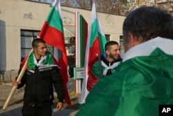 Local citizens draped in Bulgarian national flags gather in sign of protest at the fence of the Harmanli registration center as Bulgarian army soldiers are deployed in Harmanli, Bulgaria, Nov. 25, 2016.