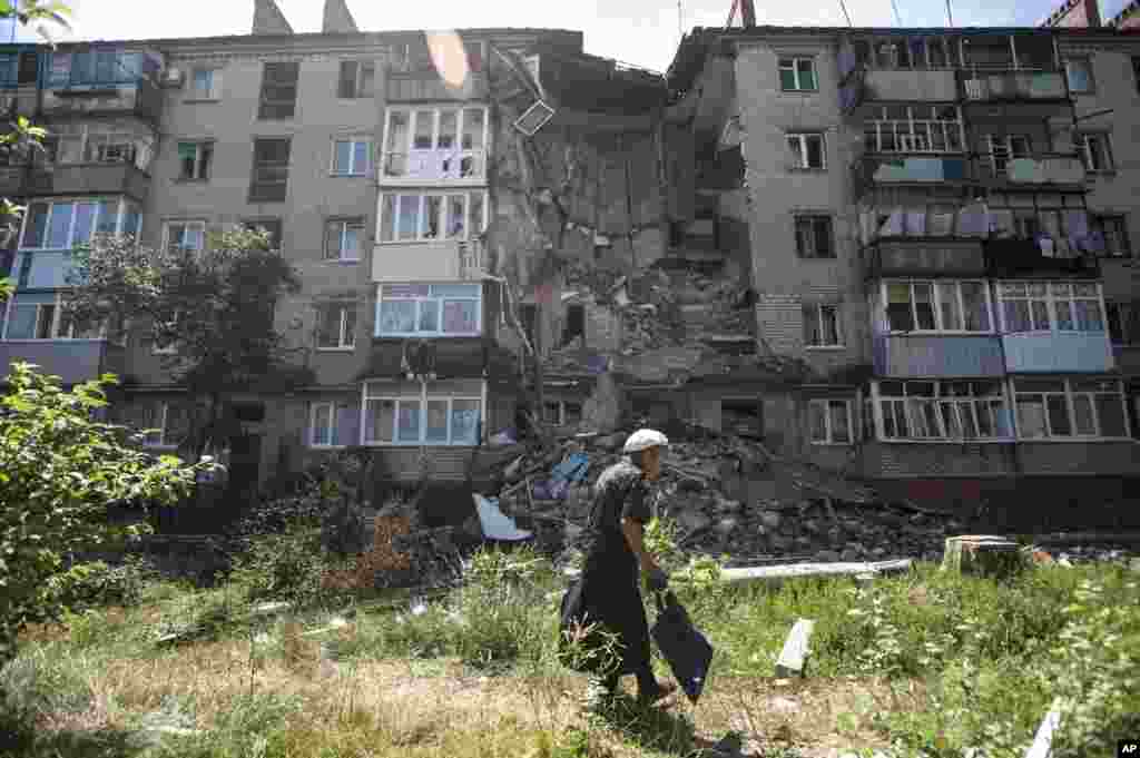 A woman walks past a building damaged by shelling in Slovyansk, eastern Ukraine, July 10, 2014. 