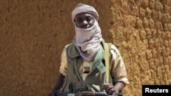 A fighter with the Tuareg separatist group MNLA (National Movement for the Liberation of Azawad) stands guard outside the local regional assembly, where members of the rebel group met with the Malian army, the UN mission in Mali and French army officers, 