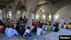 Des croyants écoutent un imam avant de manger à la fin de la journée pendant le Ramadan à Utako, à Abuja, le 16 juillet 2013.